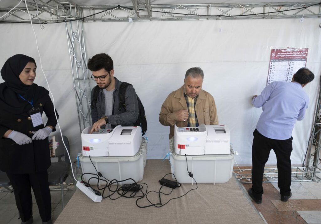 Due elettori iraniani stanno votando per la prima volta con schede elettroniche in cabine elettorali...