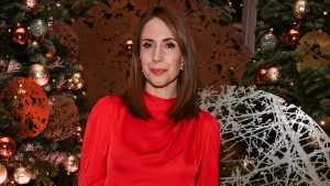 Alex Jones brilla in un elegante blouse rosso e pantaloni tartan: stile festivo impeccabile.