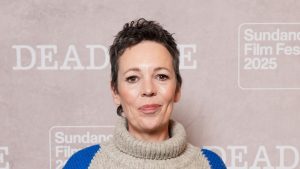 Olivia Colman veste jeans a gamba larga con maglione argyle e sneakers di suede.