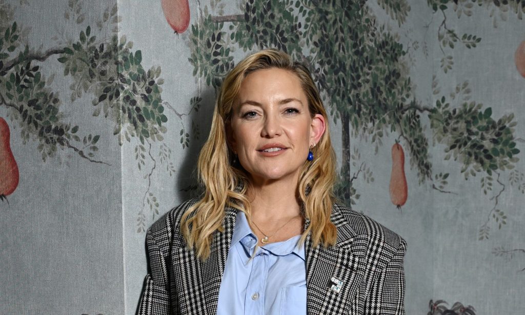 Kate Hudson sfoggia un elegante completo a quadri con camicia azzurra e slingback neri.