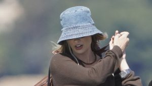 Margot Robbie incanta con un look chic: cappello in denim, jeans baggy e mocassini scamosciati.