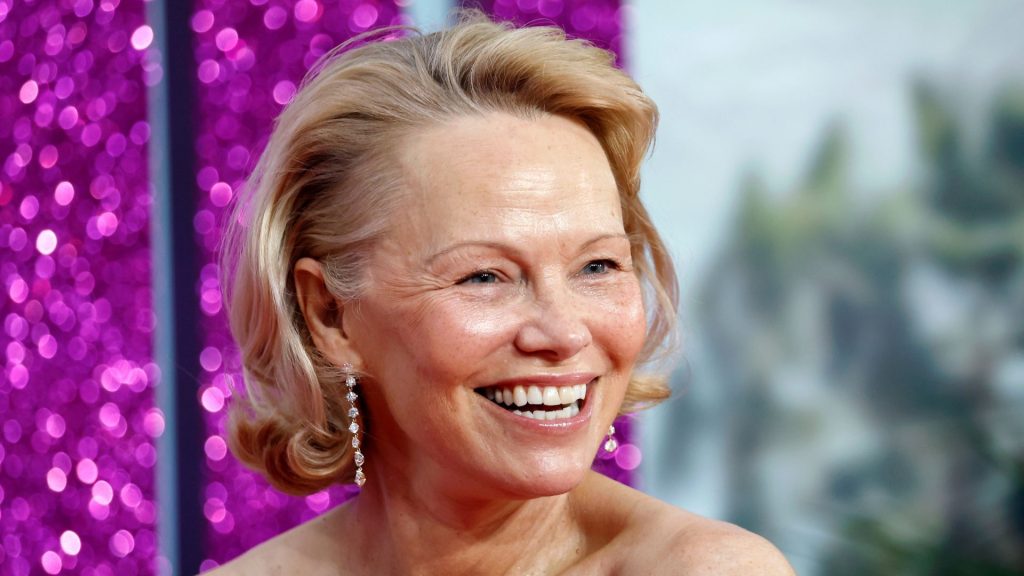 Pamela Anderson: il look perfetto con jeans straight-leg, jumper e sneakers bianche.