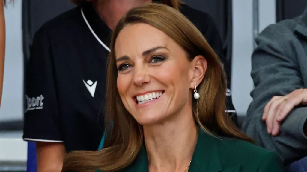 Kate Middleton affascina con un look autunnale: blazer verde, gilet a righe e gonna plissettata.