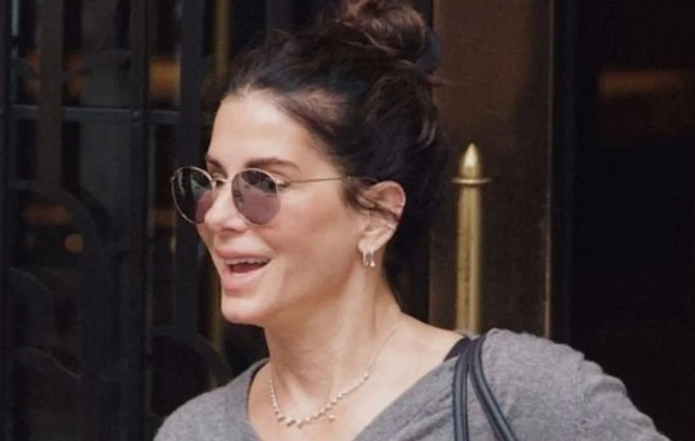Sandra Bullock’s autumn outfit: grey jumper, relaxed trousers, playful ballet flats. (pagina 2)